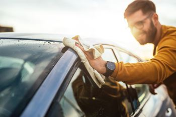 Shot of a happy young man cleaning his car with microfiber cloth on a sunny day. at Renaissance Park Apartments, Davis ,36305